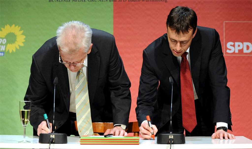 2011: Der designierte baden-württembergische Ministerpräsident Winfried Kretschmannund der designierte Minister für Finanzen und Wirtschaft, Nils Schmid (SPD), schreiben  gemeinsam ihre Namen auf den Tisch. (Archivbild).