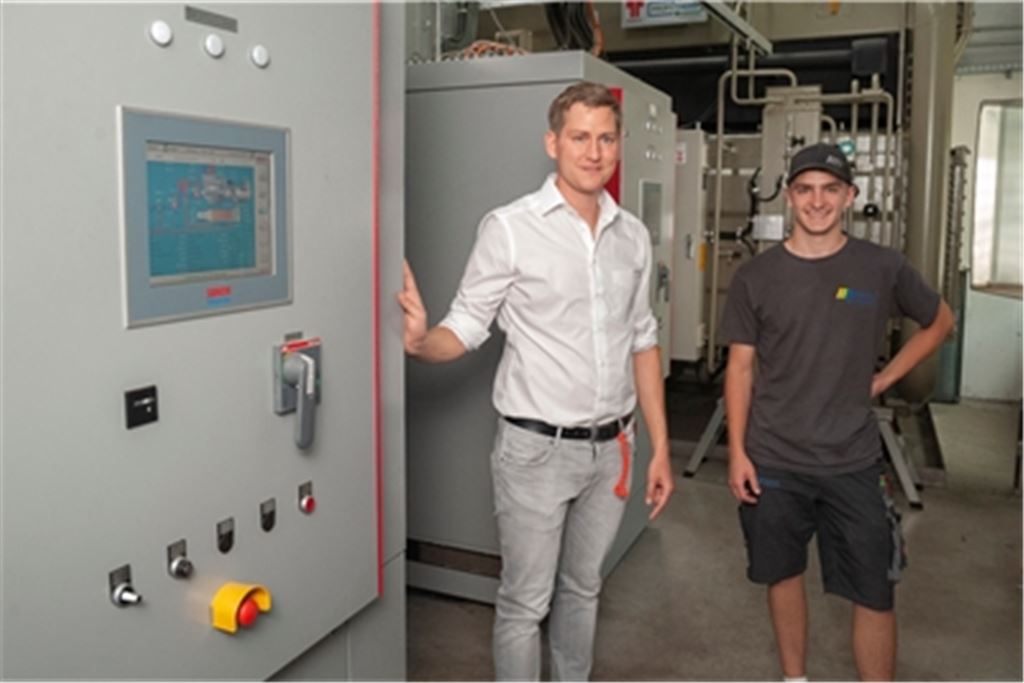 Adrian Heidinger (li.) und Elektroniker Noah Haug inmitten des Blockheizkraftwerks mit Kraft-Wärme-Kopplung bei der Firma Etzel im Gewerbegebiet Waldäcker in Mühlacker. Die Firma Heidinger hat die Anlage konzipiert und eingebaut. Heute schon können solche Anlagen zu einem gewissen Anteil mit grünem Wasserstoff betrieben werden. Fotos: Fotomoment