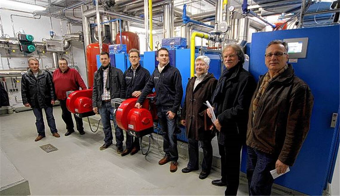 Alle freuen sich über die neue Heiztechnik am Wolfsberg (v. re.): Kreisbau-Geschäftsführer Gerhard Ayasse, Stadtwerke-Geschäftsführer Jürgen Meeh, Hausverwalterin Christa Schmid, Berndt Lustig und Ernst Wagner vom Heizungs- und Sanitärunternehmen Brüstle (Illingen), Frederik Trockel (Stadtwerke), Wolfgang Schlame (Brüstle) und Matthias Bosch (Stadtwerke) vor dem Blockheizkraftwerk und zwei Brennwertkesseln. Foto: Kollros