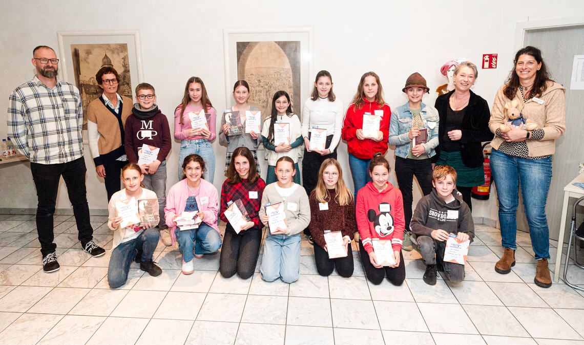 Alle sind Gewinner! Darin sind sich Organisatorin Carolin Britsch (re.) und die Mitglieder der Jury Claudia Heiler (2.v.re), Steffen Roller (hinten v.li.) und Birgit Meier einig. Buchpreise und Urkunden gibt es für alle Teilnehmerinnen und Teilnehmer. Dies sind (kniend v.li.) Sarah-Louisa Schneider, Vanesa Beciri Rodriguez, Lea Kustos, Leni Jäger, Ayleen Schurlik, Helene Ugi und Kai Mangold sowie (hintere Reihe v.li.) Julius Fritz, Imranur Kurdes, Ellen Herdt, Carla Grohmann, Alicia Peter, Emilia Bürkle und Emma Duczek. Fotos: Fotomoment