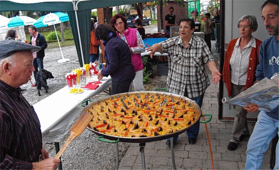 „Alles fertig!“, gibt Isabel Naranjo (Mitte) das Kommando zum Abdecken der Pfanne. Ehemann Francisco (li.) hat mitgerührt, während Sohn Miguel (re.) der „Maître an der Pfanne“ ist. Foto: Filitz