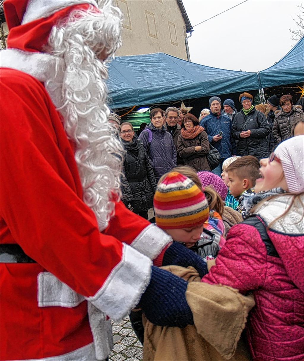 Als Dankeschön für ihren Liedvortrag dürfen alle Chorkinder in den gefüllten Nikolaussack greifen. Mitte: Annsophie interessiert sich für Nussknacker. Rechts: Helga Seiter-Neininger mit „Tatzen“. Fotos: Filitz