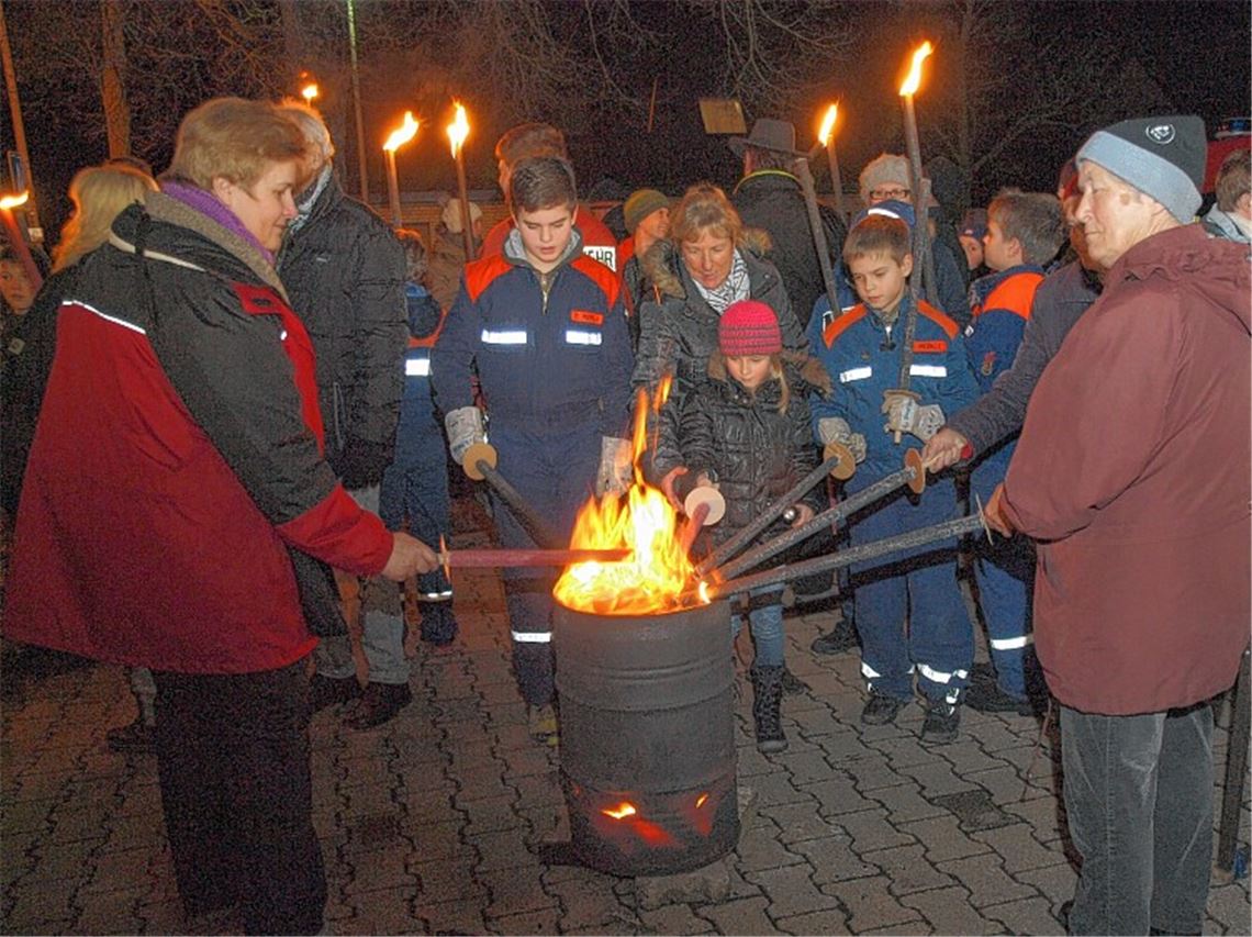 Am lodernden Blechfass vor dem Feuerwehrmagazin Zaisersweiher werden die Fackeln angezündet. Foto: Appich