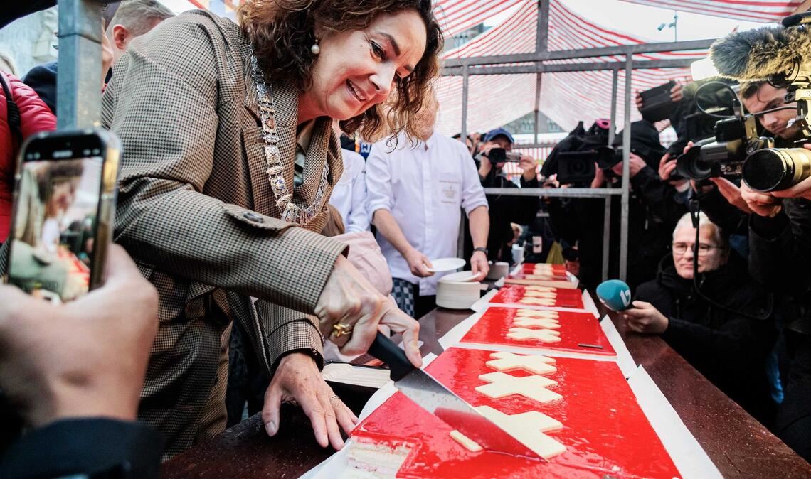 Amsterdams Bürgermeisterin Femke Halsema schneidet die lange Torte an.