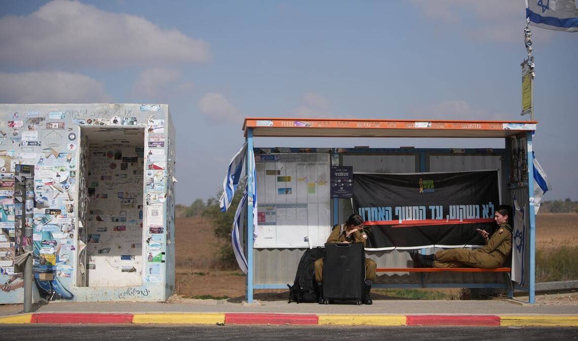 An einem Busbahnhof nahe der Grenze zum Gazastreifen warten israelische Soldatinnen auf den Transport.