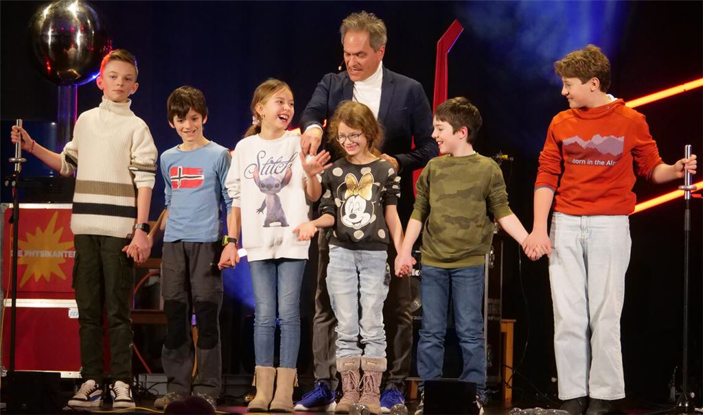Anschaulich beweist Thomas Müller von den „Physikanten“, dass Strom durch eine Menschenkette, bestehend aus Kindern aus dem Publikum, fließen kann. Fotos: Friedrich