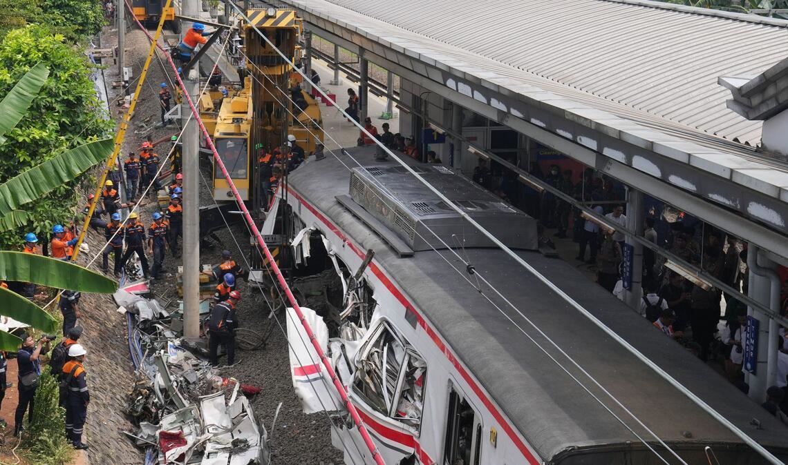 Arbeiter setzen eine schwere Maschine ein, um die Trümmer eines Zuges nach einer Kollision in Bekasi, Indonesien, zu beseitigen.