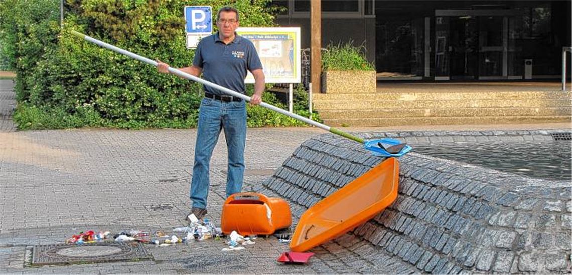 „Arbeitseinsatz“ der unerfreulichen Art: Betriebsleiter Rudi Pfisterer fischt am Morgen danach den Müll aus der Brunnenanlage vor dem Eingang zum Hallenbad.