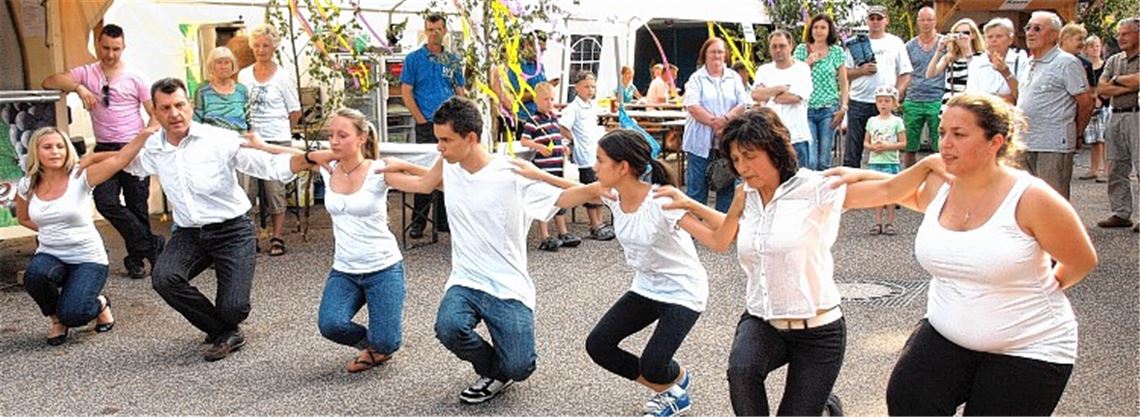 Arbeitsteilung beim Wiernsheimer Straßenfest: Während Ehemann Karlheinz den Fassanstich problemlos bewältigt, reiht sich Sevasti Oehler (Bild unten, 2. v. re.) in der Volkstanzgruppe ein.