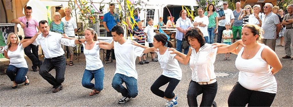 Arbeitsteilung beim Wiernsheimer Straßenfest: Während Ehemann Karlheinz den Fassanstich problemlos bewältigt, reiht sich Sevasti Oehler (Bild unten, 2. v. re.) in der Volkstanzgruppe ein.