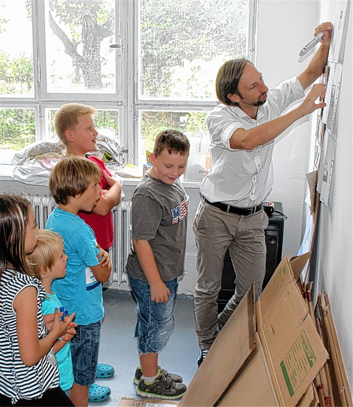 Architekt Julian Wolf erklärt den Kindern beim Kinderferienprogramm zunächst Grundrisse, Schnitte und Ansichten von Häusern. Und dann wird selbst gebaut und gestrichen.