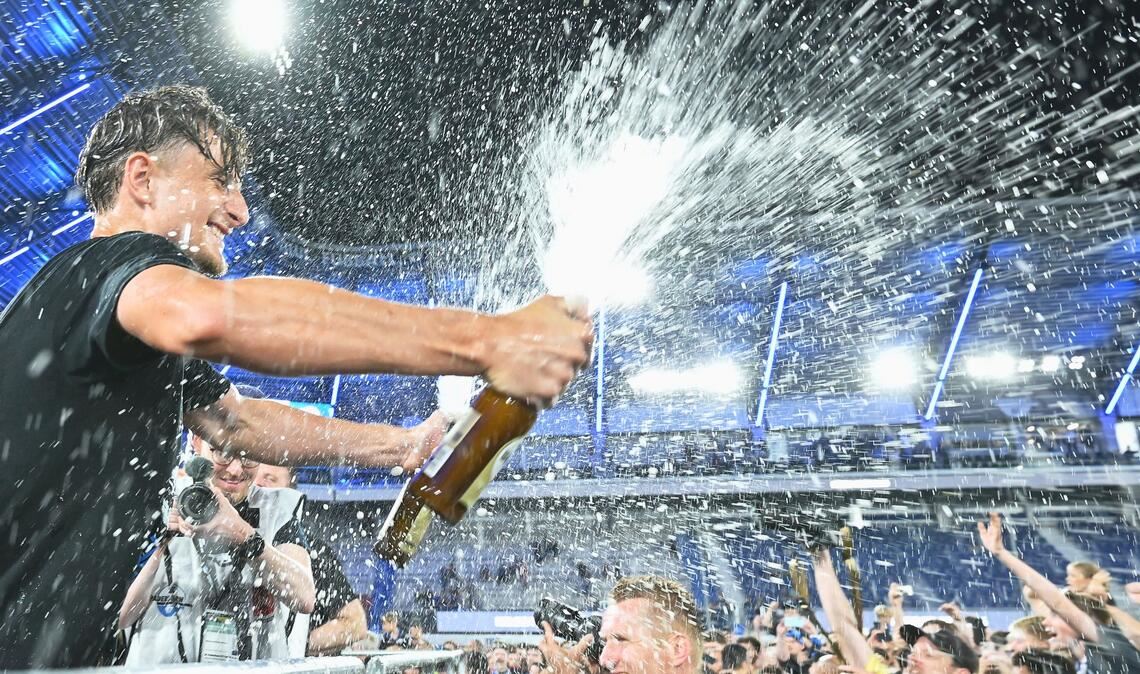 Arena. Spieler von SC Paderborn 07 spritzt mit einer Sektflasche im Stadion.