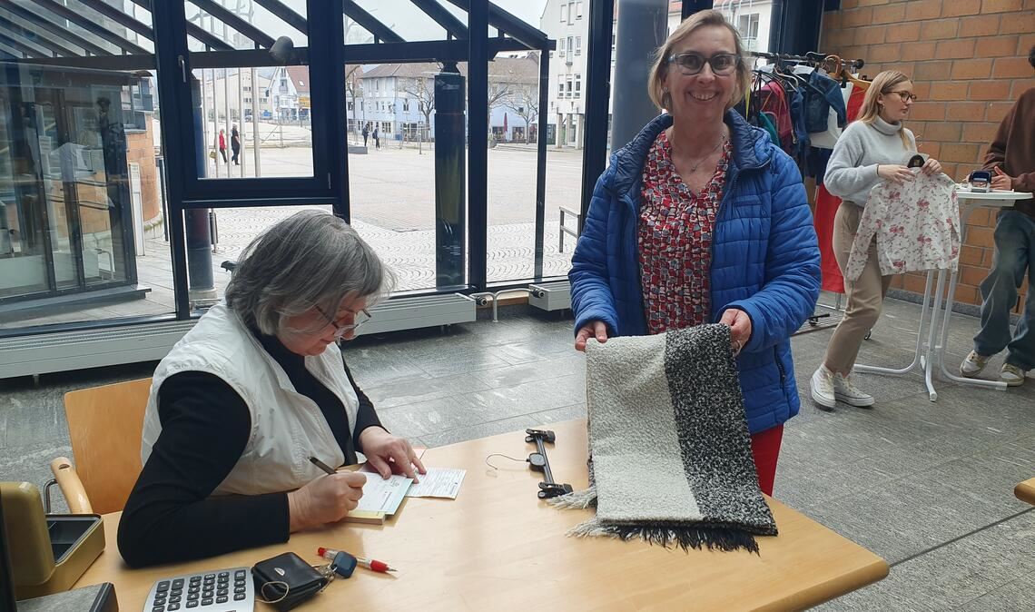 Auch ein Schal wechselt im Rathausfoyer die Besitzerin. Ulrike Gutmann-von-Langsdorff (li,), die Leiterin des Fundbüros, muss den Käufern detaillierte Quittungen ausstellen. Foto: Schröder