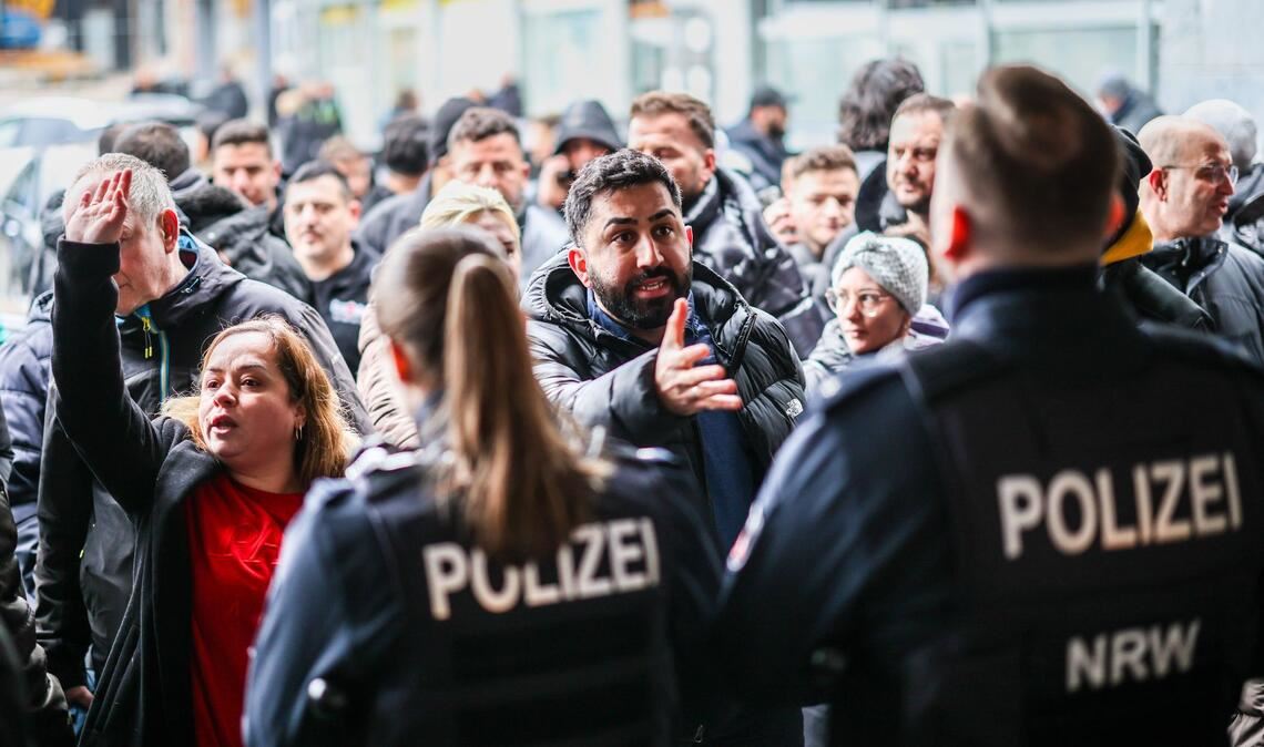 Aufgebrachte Kunden diskutieren vor der Sparkassenfiliale in Buer mit Polizeibeamten nach der Räumung des Vorraums der Filiale.
