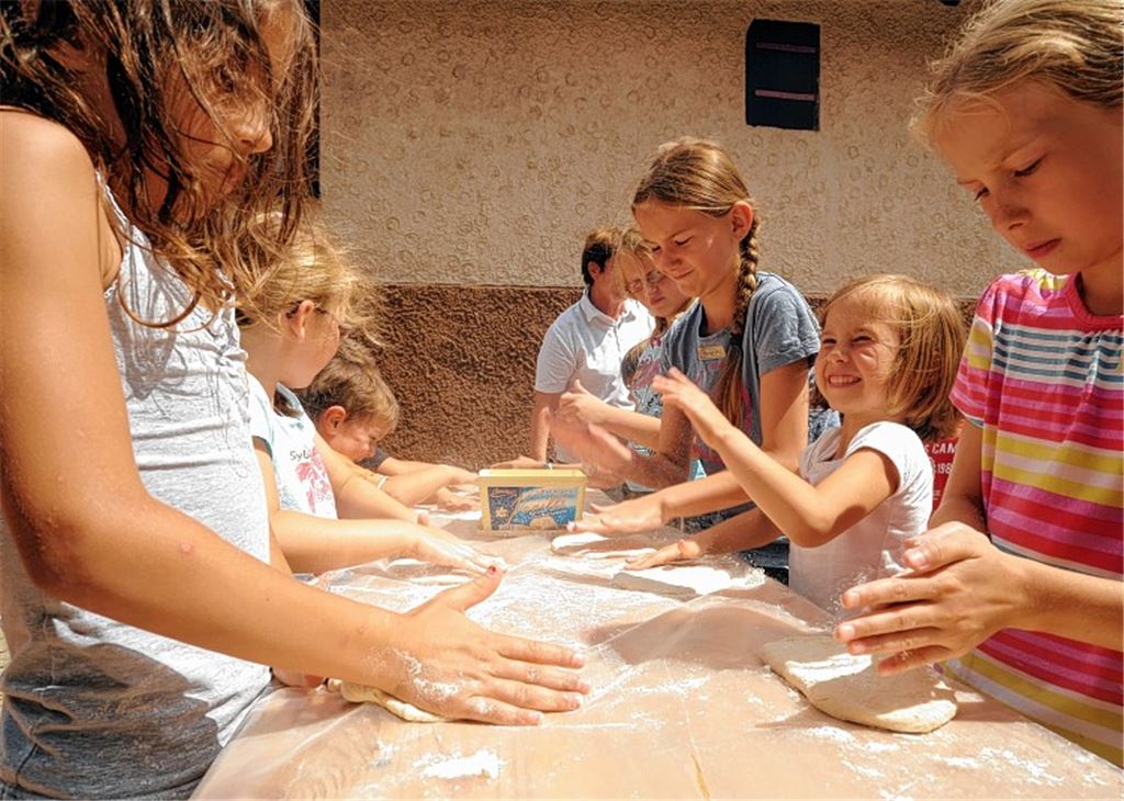 Aus den Teigkugeln stellen die Kinder mit spielerischer Laune Pizzaböden her, die später belegt werden und ins Backhaus kommen. Foto: Fotomoment