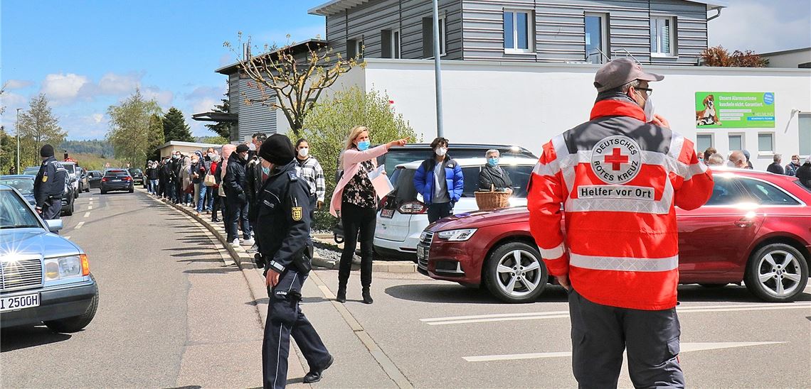 Ausnahmezustand in Huchenfeld: Ortsvorsteherin Sabine Wagner weist den Weg, Polizei und DRK-Helfer dirigieren links wartende Autos, in der Mitte stehen Impfwillige ohne Auto an. Wewoda