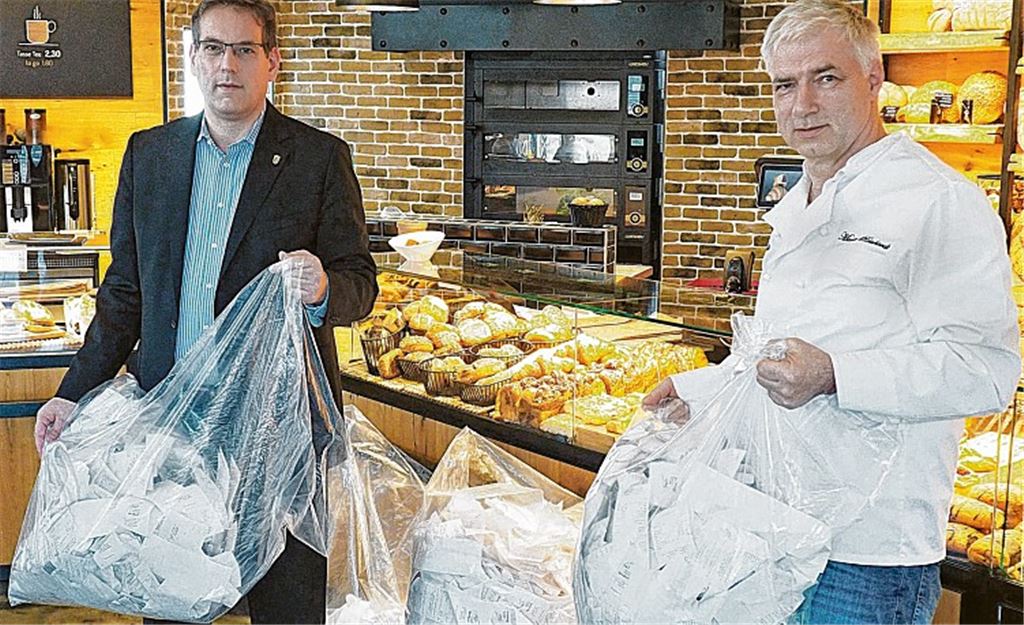 Bäckermeister Martin Reinhardt (re.) übergibt dem FDP-Landtagsabgeordneten Erik Schweickert im Geschäft liegengebliebene Kassenbons. Foto: Müller