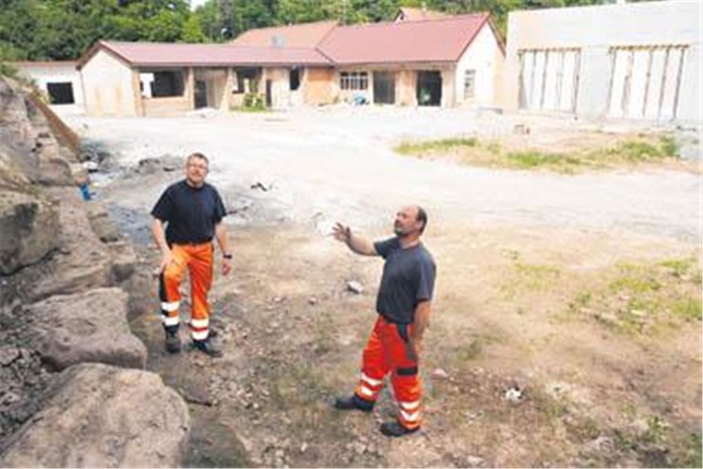 Bauhofleiter Manfred Bohn (li.) und Mitarbeiter Hans Wagner am künftigen Standort im ehemaligen Steinbruchgelände am Maulbronner Stadtrand. Im Hintergrund steht das L-förmige Hauptgebäude, das unter anderem Werkstatträume und Büros beherbergen wird. Foto: Fotomoment