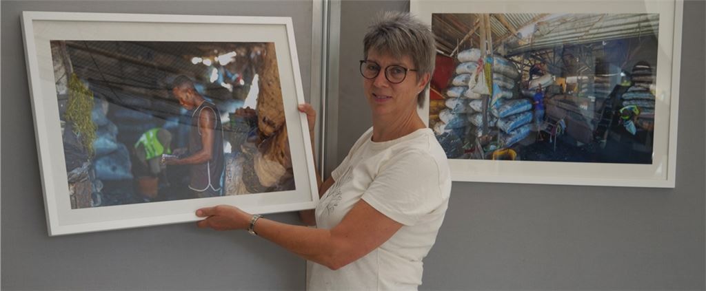 Bei der Hängung der Fotografien kündigt Angela Gewiese Einblicke in die Produktion von Holzkohle in Tansania an, von der dort Millionen Menschen abhängig sind. Foto: Friedrich