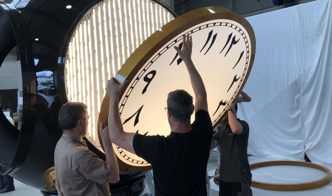 Beim Testaufbau einer 14 Meter hohen Säulenuhr für Doha passen Perrot-Mitarbeiter  das Zifferblatt in den Korpus ein.