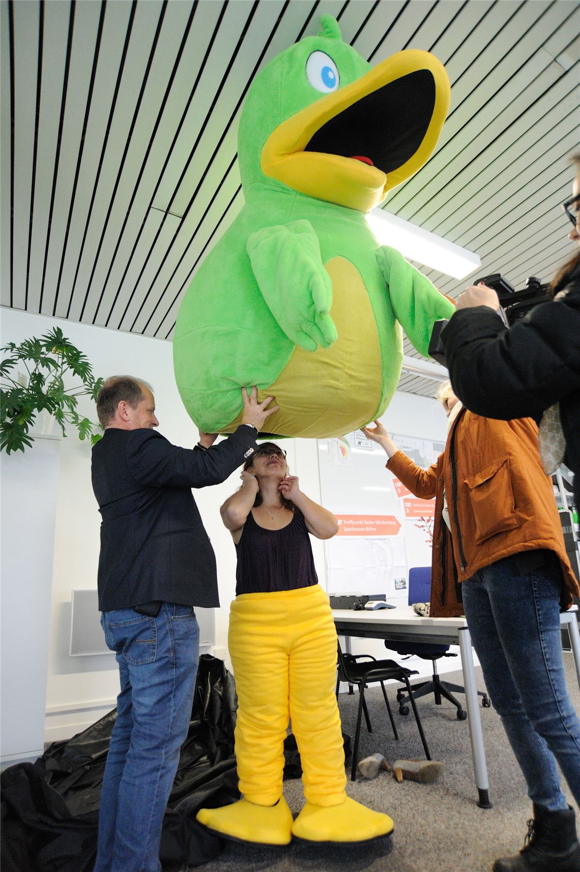 Beim Überstülpen des sperrigen Federkleids hilft unter anderem Bürgermeister Winfried Abicht.