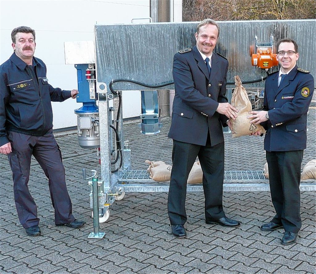 Bernd Braun (v.li.), Ortsbeauftragter des THW Pforzheim, mit dem Kreisbrandmeister des Enzkreises, Christian Spielvogel, und Pforzheims Feuerwehrkommandant Sebastian Fischer vor der neuen Sandsackfüllmaschine.