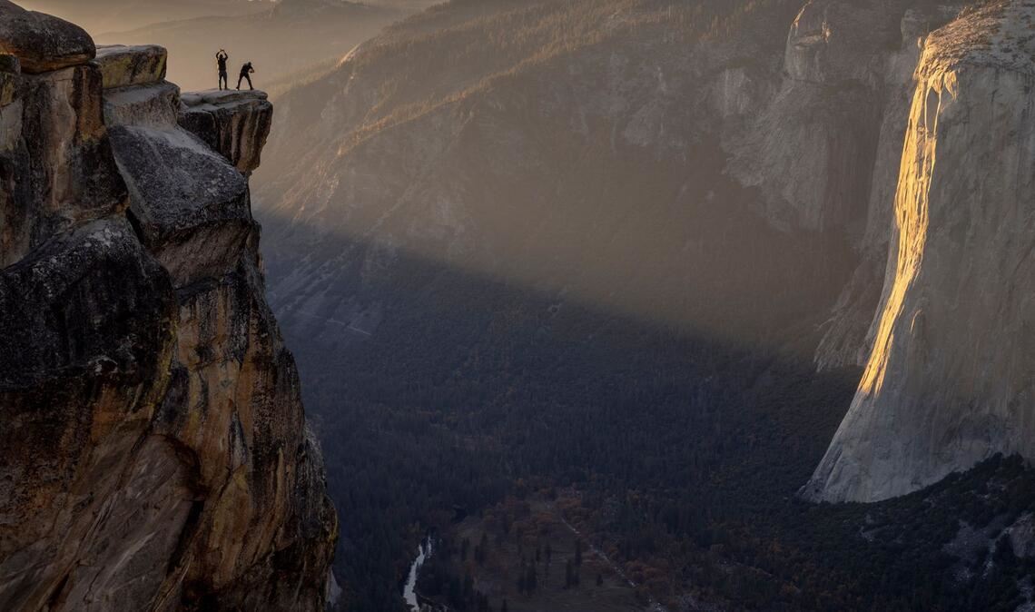Besucher posieren für ein Foto auf einem Felsvorsprung in der Nähe von Taft Point im Yosemite Nationalpark in den USA.