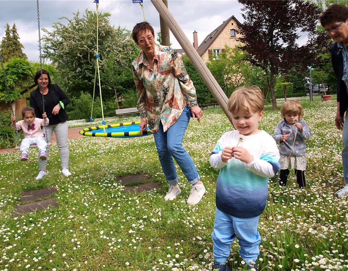 Betreuung schon im Kleinkindalter bietet das Mehrgenerationenhaus Mühlacker. Auch der Garten ist eine Spielwiese. V.li. Sylvia Dilger, die Isabella schaukelt, Alexandra Rapp, die Elvis vormacht, wie er die Pusteblume anpusten muss, und Rosemarie Scheipner, die der kleinen Antonia eine Pusteblume erklärt. Foto: Filitz