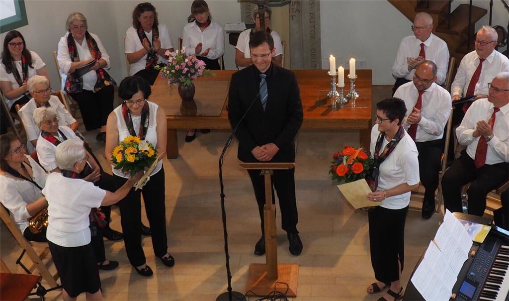 Bezirkskantor Thorsten Hülsemann (Mitte) ehrt die Sängerinnen Anita Ehniss (li. mit Strauß) und Esther Britz (re. mit Strauß) für langjähriges Singen. Foto: Müller