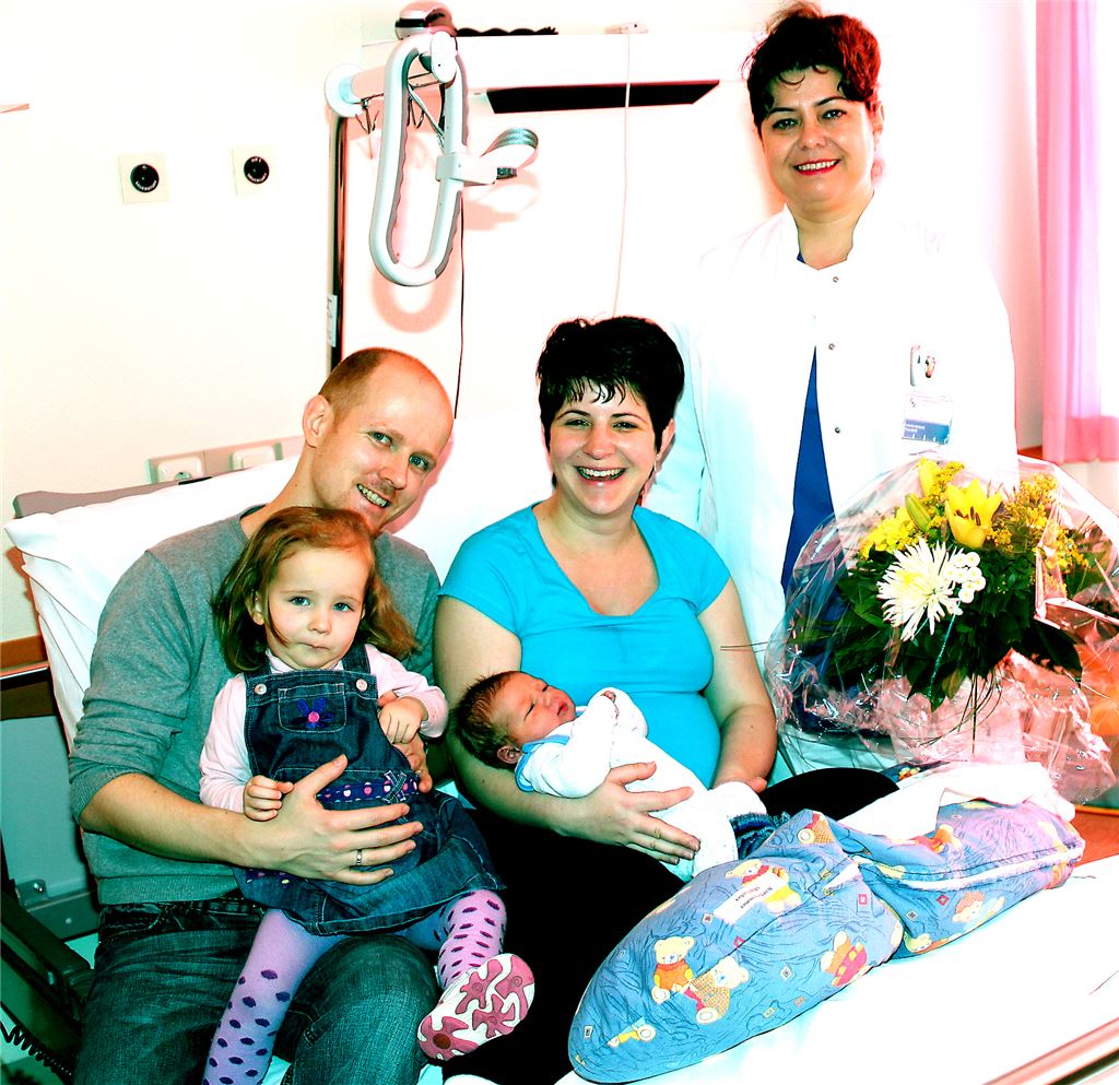 Oberärztin Müller überreicht der Mutter des Neujahrsbabys einen Blumengruß der Klinik, Ehemann Florian Ascherl freut sich ebenso über den Zuwachs wie Töchterchen Annica Mira. Foto: Kollros