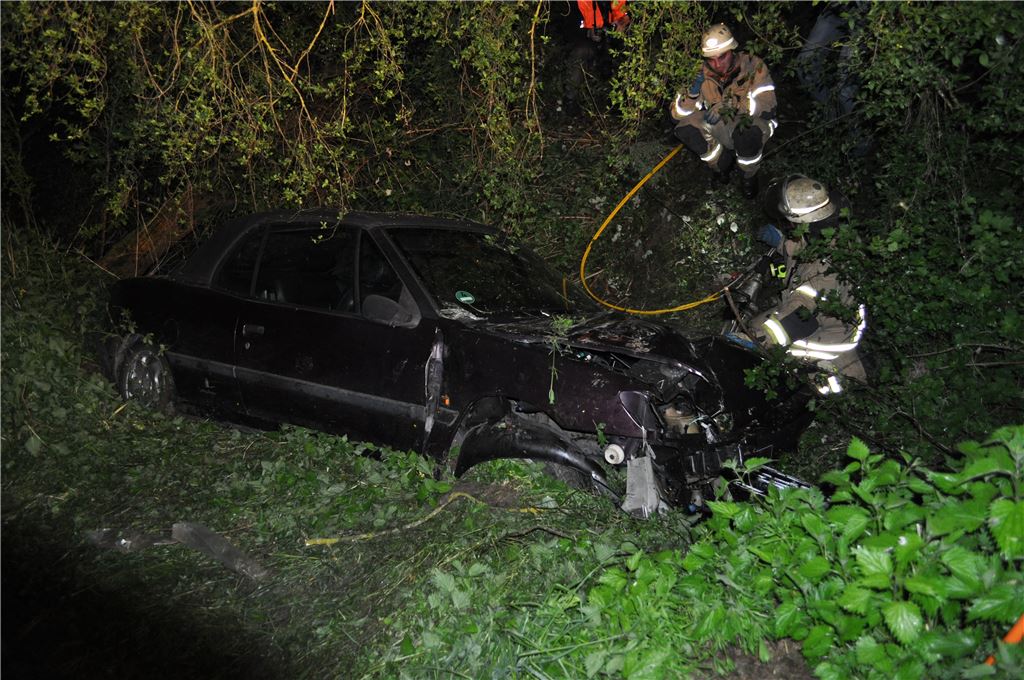 Schwieriger Rettungseinsatz: Die Feuerwehr muss die drei Insassen, darunter ein neunjähriges Kind, aus dem im Bachbett eingekeilten Unfallwagen befreien.  Foto: 