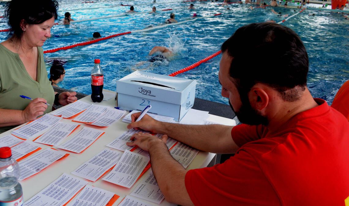 Marika Hofmann und Ali Ünsal zählen die Bahnen der schnellen Schwimmer.