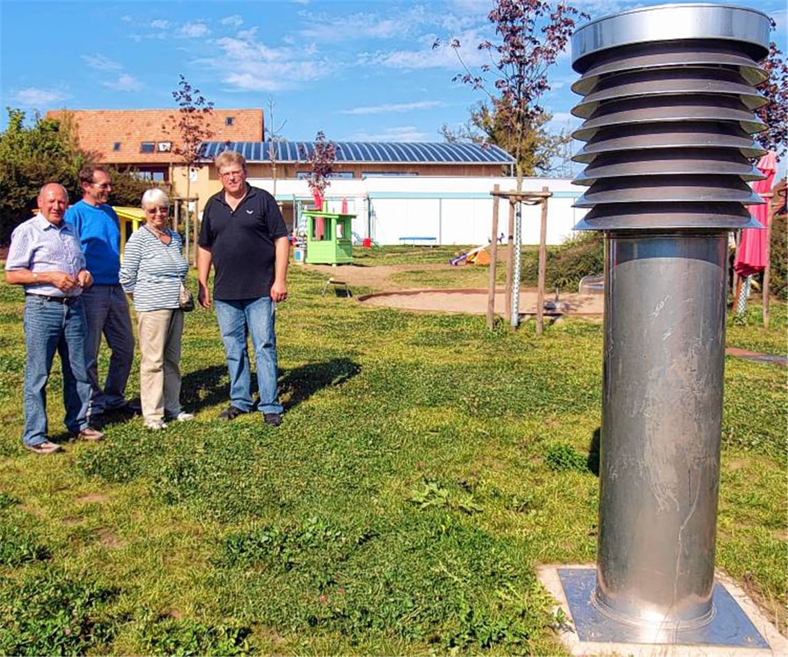 Bild links: Energieberater Ralf Schmauder (re.) zeigt Besuchern den Ansaugstutzen für die Frischluft im Garten. Im Hintergrund ist das mit Silizium beschichtete Dach des Kindergartens Serres zu sehen. Im Technikraum (rechtes Bild) nehmen die interessierten Gäste die Haustechnik unter die Lupe, darunter den Verlauf der Zu- und Abluftkanäle und die umfangreiche Filteranlage für die Zuluft.