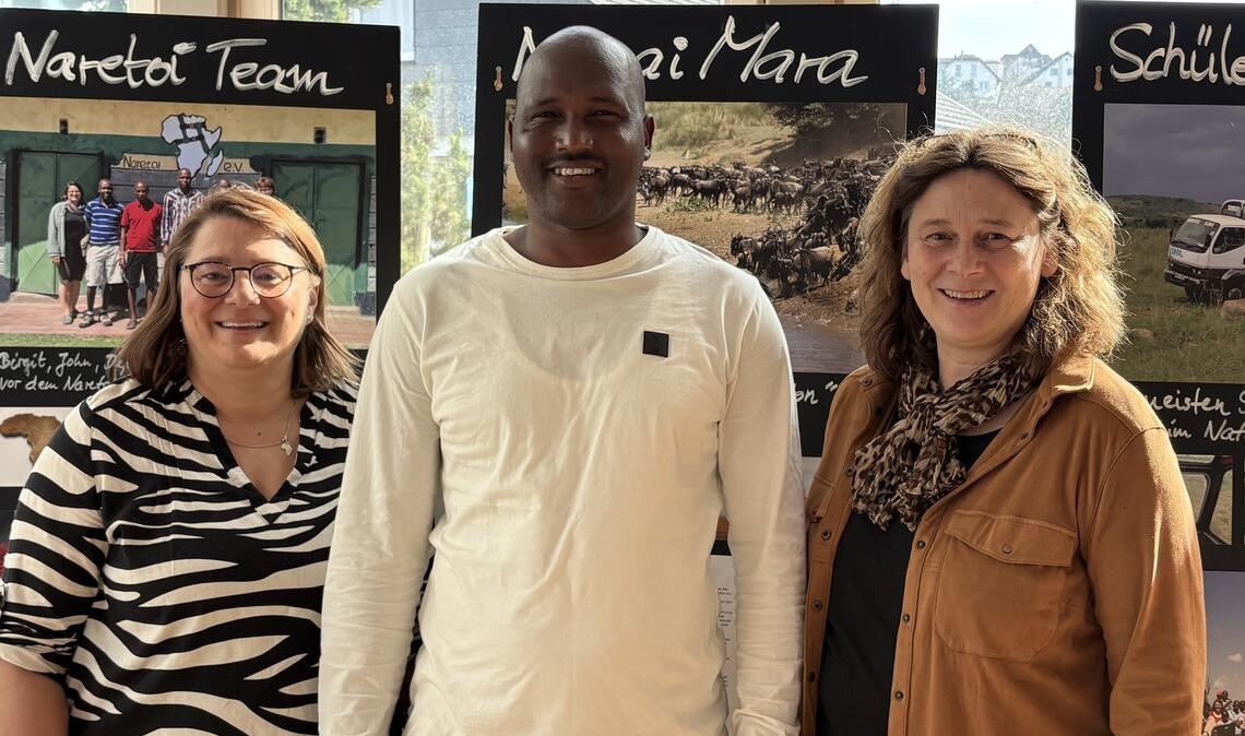 Birgit Faas (li.) mit Heike Längle und Moses Sikona von „Naretoi Kenia“, dem Partnerverein. Hinter ihnen ist die Ausstellung zu sehen mit Fotos von den Szenerien und den Projekten, die wie eine Dokumentation angelegt ist. Foto: privat