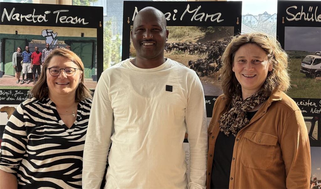 Birgit Faas (li.) mit Heike Längle und Moses Sikona von „Naretoi Kenia“, dem Partnerverein. Hinter ihnen ist die Ausstellung zu sehen mit Fotos von den Szenerien und den Projekten, die wie eine Dokumentation angelegt ist. Foto: privat