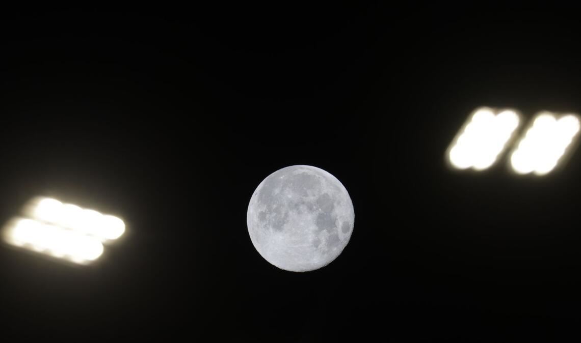 Blick auf den Mond zwischen Straßenlaternen in Riedlingen.