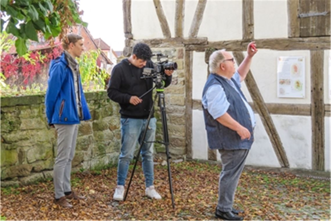 Blick über die Schulter: Tim Richter (li.) und Christian Steinbrenner von Grasshopper Kreativ aus Tübingen setzen Günter Bächle für einen Filmbeitrag in Szene. Bächle selbst schaut durch sein Smartphone auf die Peterskirche – nur eines der bemerkenswerten Gebäude in jenem Dorf, dessen Geschichte der Stadtrat immer wieder neu beleuchtet. Foto: Becker