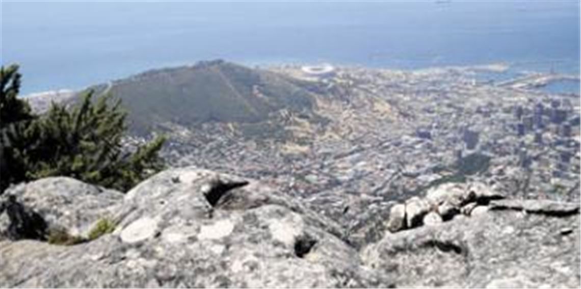 Blick vom Tafelberg auf Kapstadt mit seinem WM-Stadion (Bildmitte, direkt an der Küste). Die beeindruckenden Ansichten in Südafrika passen nicht immer zu den inneren Problemen des Landes. Foto: p