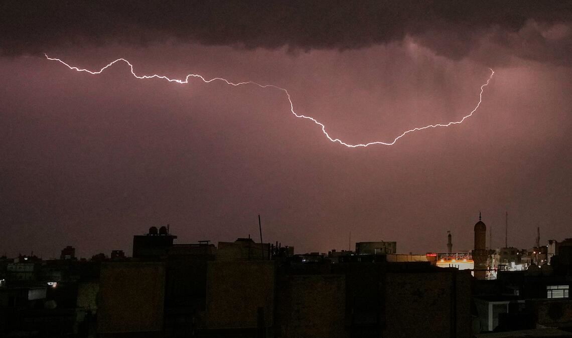 Blitze erhellen den Himmel, während ein Gewitter über Bagdad hinwegzieht.