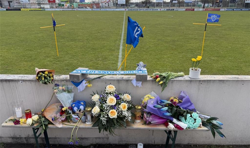 Blumen und Kerzen sind an einem Fußballplatz im Ortsteil Bruck aufgestellt.