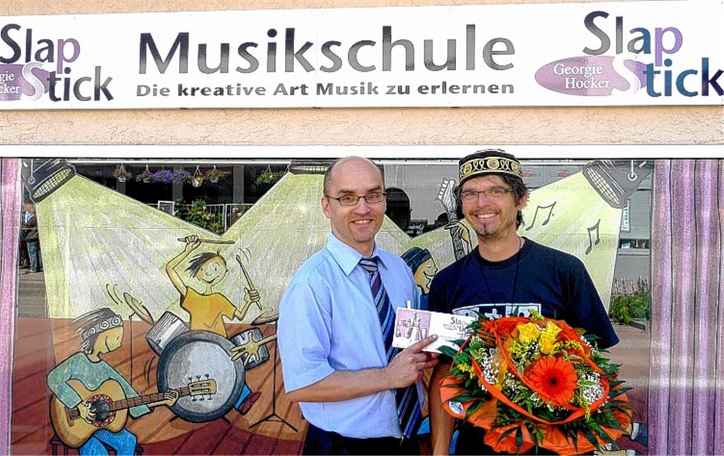 Blumen vom Bürgermeister zum Start in Illingen: Harald Eiberger (li.) gratuliert Georgie Hocker zur Neueröffnung seiner Musikschule an der Bahnhofstraße. Foto: privat