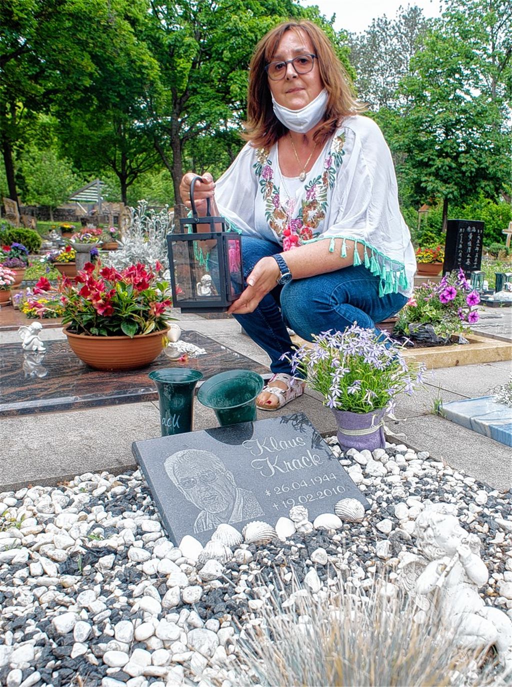 Brigitte Krack mit Laterne am Grab ihres Schwiegervaters.Foto: Fotomoment