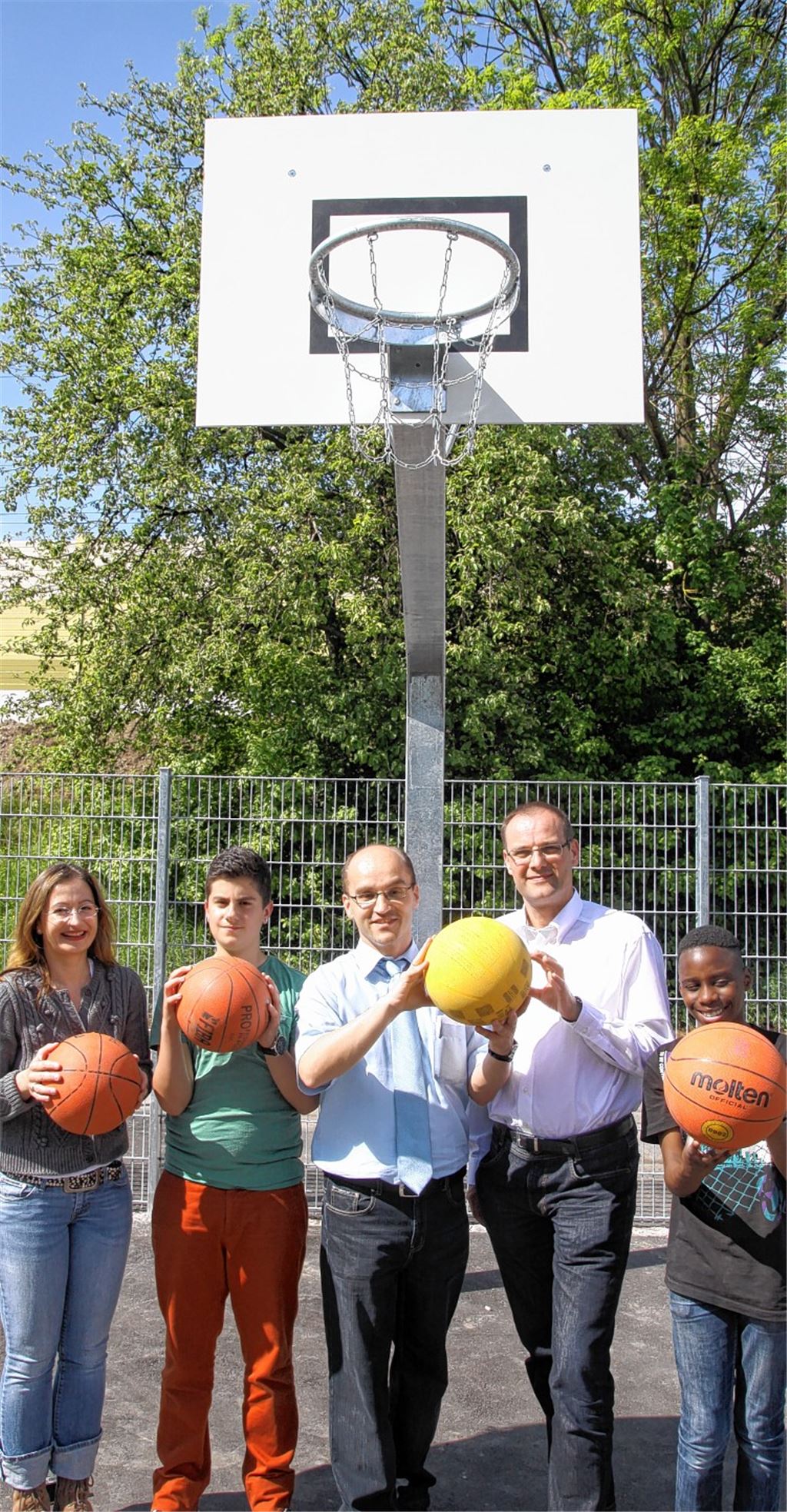 Bürgermeister Harald Eiberger (Mitte), Bauamtsleiter Thomas Mörmann (2. v. re.) und Schulsozialarbeiterin Regina Wahl (li.) freuen sich gemeinsam mit Jugendlichen über das Ballspielfeld in der Illinger Talaue.