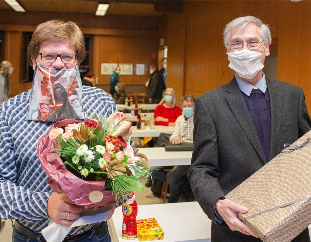 Bürgermeister Karlheinz Oehler (links im Bild, neben ihm Wolfgang Hanisch) erhält Blumen und Bücher zum Dienstjubiläum. Fotomoment