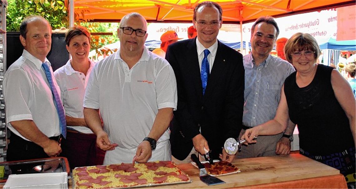 Bürgermeister Winfried Abicht (v.li.), Beate und Hans-Dieter Slobodkin, CDU-Bundestagsabgeordneter Gunther Krichbaum, Markus Schellinger, Leiter von St. Franziskus, und Monika Malkowski, Vorsitzende der Stiftung St. Franziskus, schneiden beim Sommerfest die Pizza an. Foto: Stahlfeld