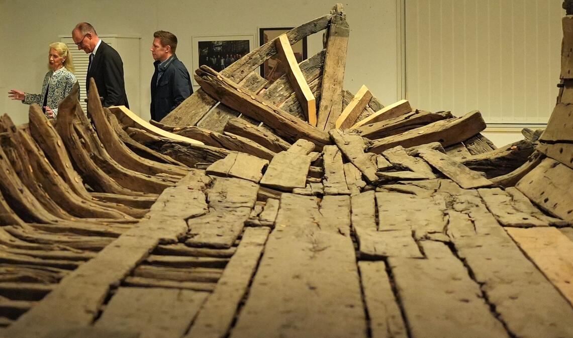 Bundeskanzler Friedrich Merz (2.v.l, CDU) geht mit Museumsdirektorin Astrid Cohrs-Dreessen (l) nach einer Pressekonferenz im Schifffahrtsmuseum Nordfriesland an dem "Zuckerschiff" vorbei.