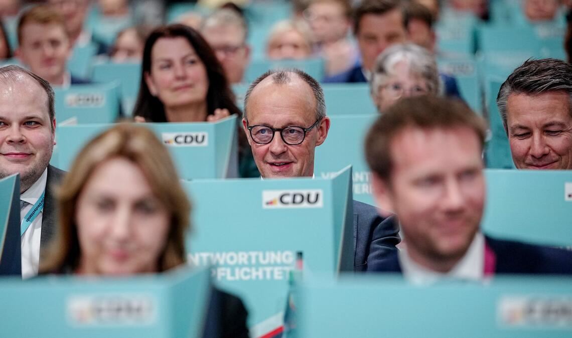 Bundeskanzler Friedrich Merz (M), CDU-Parteivorsitzender, sitzt hinter seiner Wahlkabine.