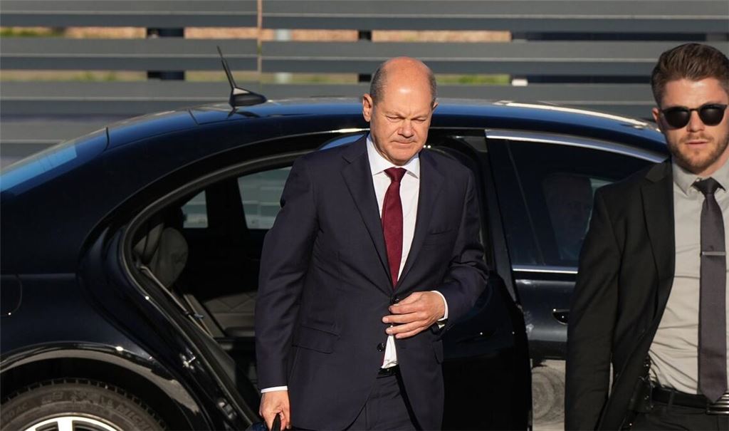 Bundeskanzler Olaf Scholz (l, SPD) kommt zum Start einer zweitägigen Reise auf dem militärischen Teil des Flughafens Berlin Brandenburg BER an und steigt aus einer Limousine.