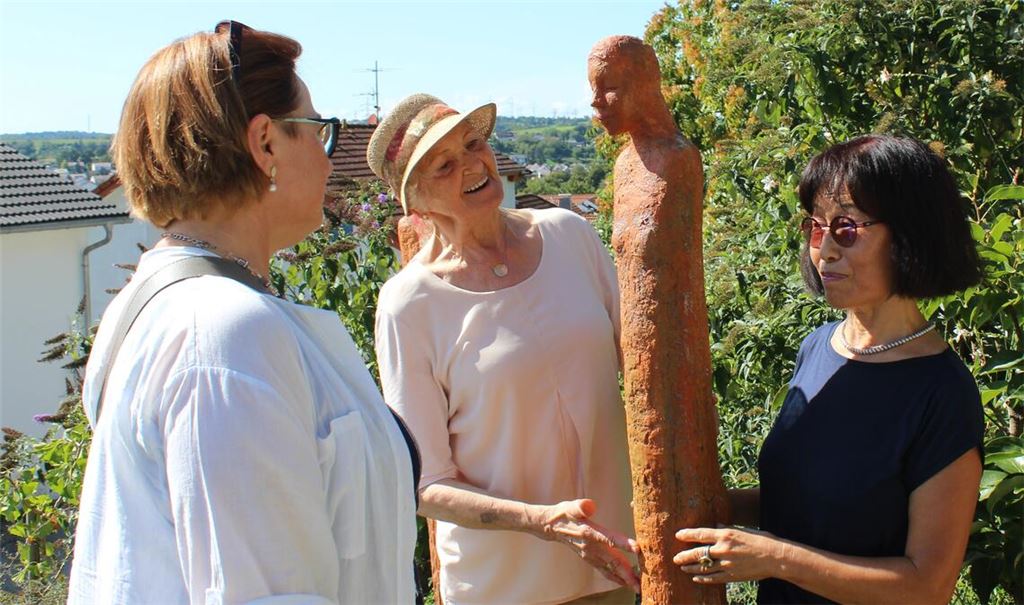Chong-Im Neukamm (re.) im Gespräch mit zwei Besucherinnen, die sich ihre Kunstwerke im Garten anschauen. Fotos: Gießler