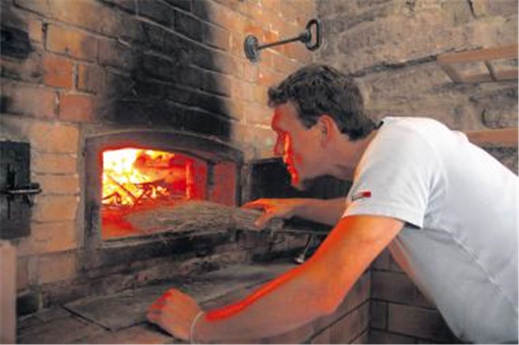 Christian Schramm heizt ab sofort das Schützinger Backhaus an. Die Gemeinde hat das Kleinod hinter dem Rathaus aufwändig saniert. Foto: Hansen